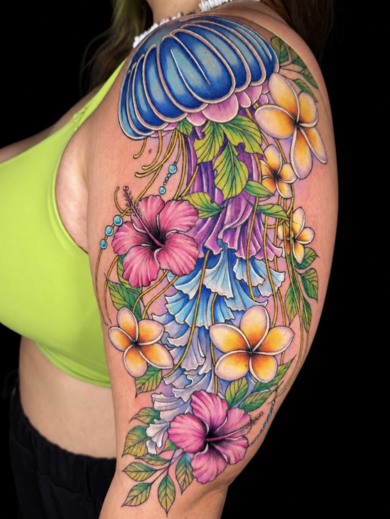 Color jellyfish with hibiscus and plumeria shoulder tattoo by Jorge Moreira at Moreira Ink Tattoo Shop, Lake Alfred FL